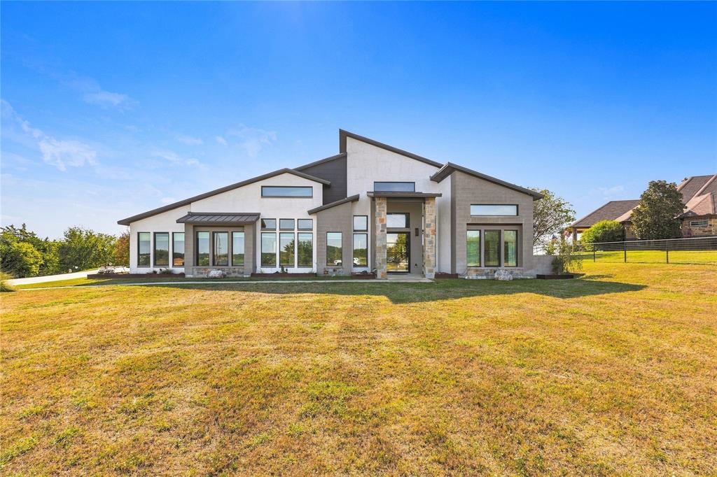 Modern exterior featuring a multi-gabled roofline, stone masonry accents, a stucco facade, and oversized picture windows