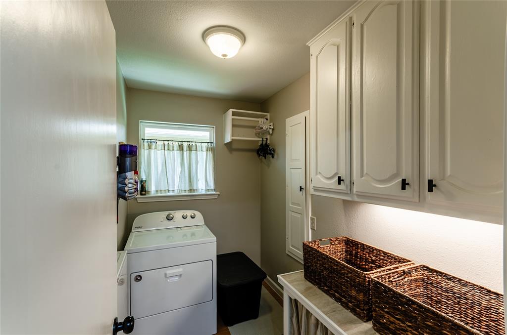 White cabinetry with dark hardware, built-in shelving, and a window for natural light