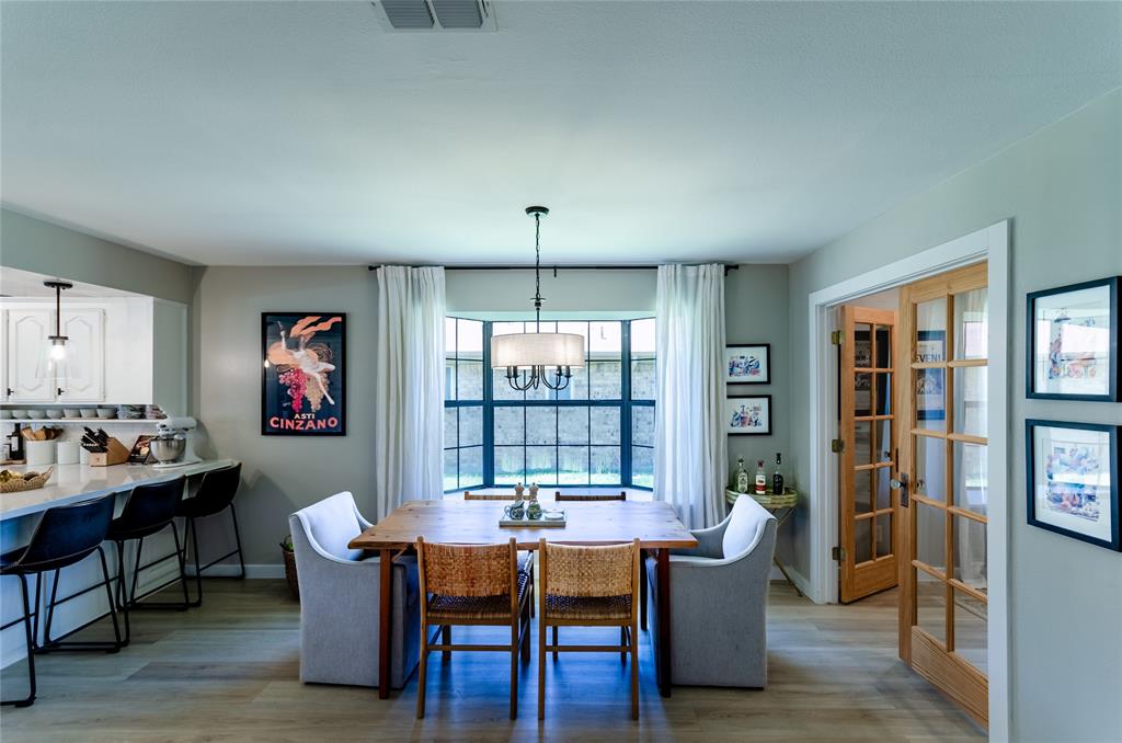 Bay window with black framing, wood-finish flooring, recessed lighting, and a chandelier-style pendant light