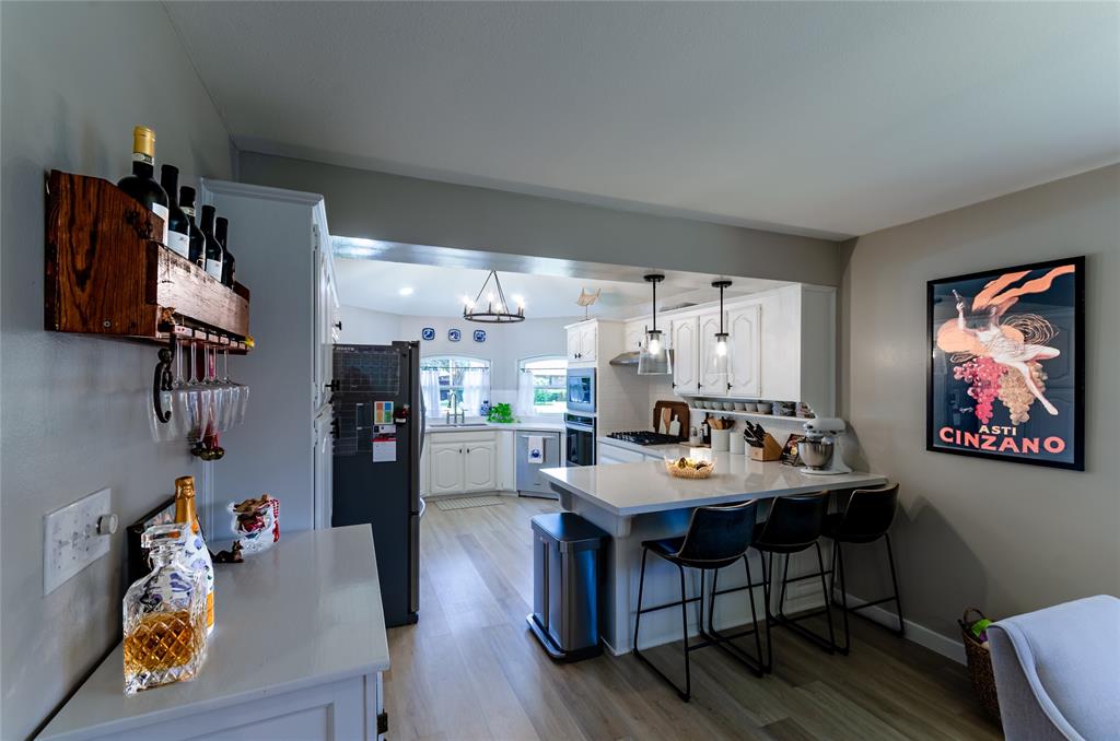 Kitchen featuring white cabinetry, a central island with countertop seating, stainless steel appliances, and pendant lighting