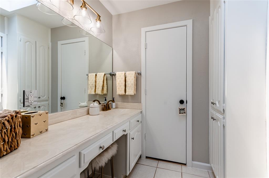 White vanity with integrated countertop, vanity seating area, built-in storage cabinetry, and wall-mounted light fixture