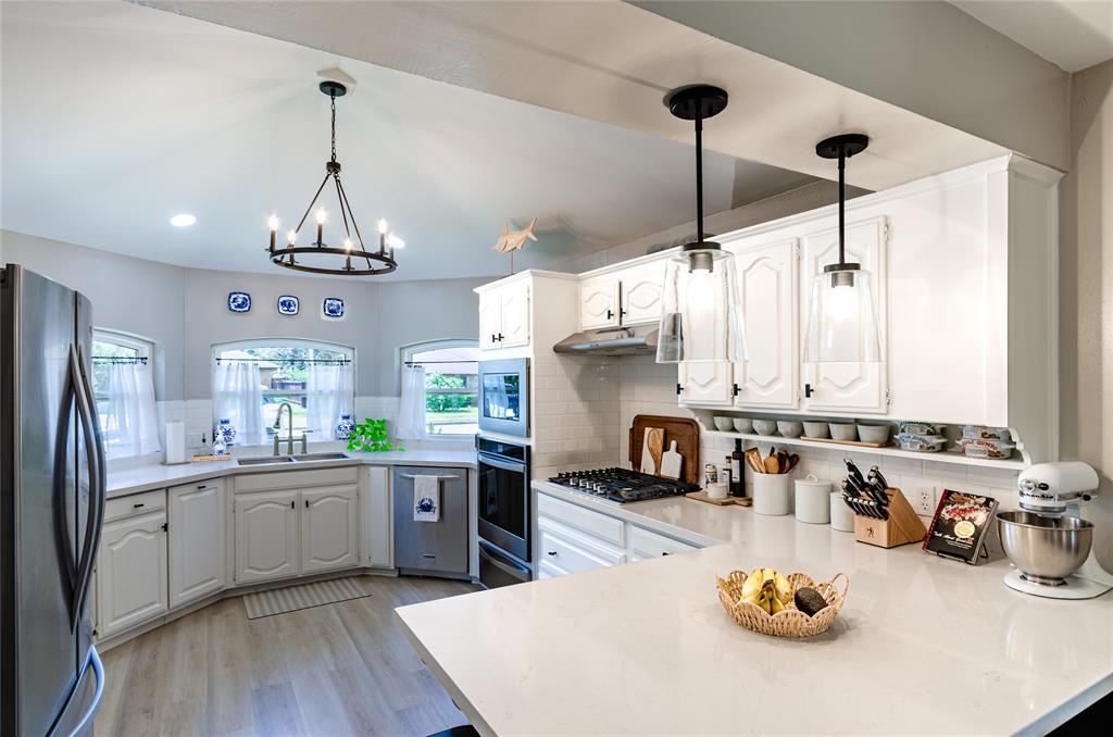 White cabinetry, stainless steel appliances, built-in microwave, gas cooktop, and light-toned countertops