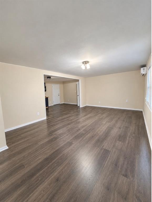 Open-concept area featuring wood-finish flooring, a wall-mounted ductless cooling unit, and central overhead lighting