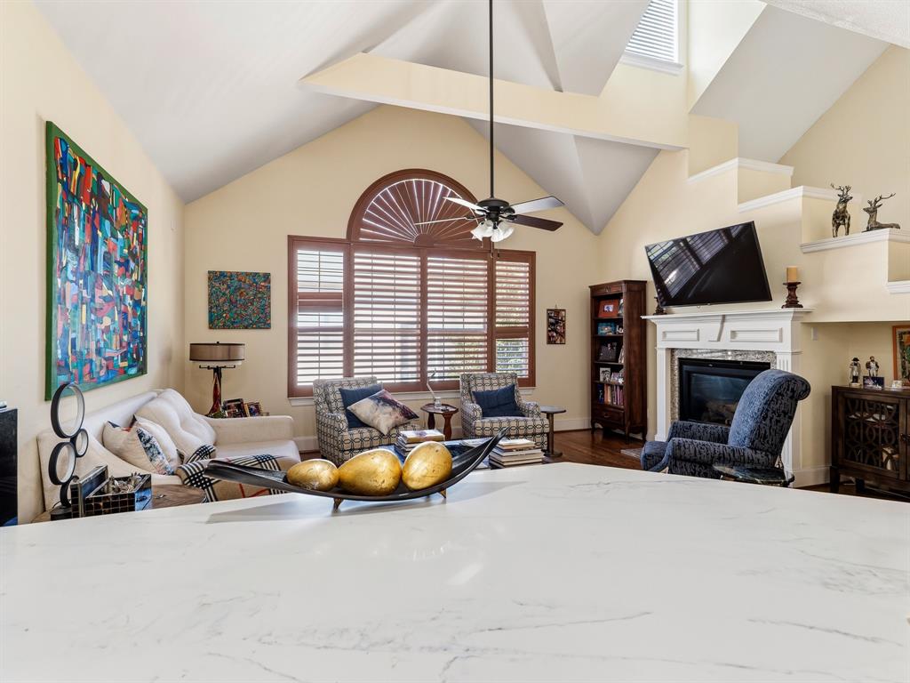 Vaulted ceilings, fireplace with custom mantel, arched window with wood-finish shutters, and expansive stone-surface countertop Vaulted ceilings, fireplace with custom mantel, arched window with wood-finish shutters, and expansive stone-surface countertop