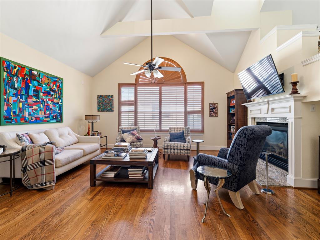 Vaulted ceiling, wood-finish flooring, fireplace with custom mantel, arched window, and ceiling fan Vaulted ceiling, wood-finish flooring, fireplace with custom mantel, arched window, and ceiling fan