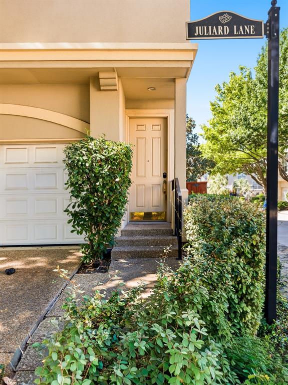 Exterior entrance featuring a six-panel front door, concrete steps, and a multi-section garage door with an arched header Exterior entrance featuring a six-panel front door, concrete steps, and a multi-section garage door with an arched header