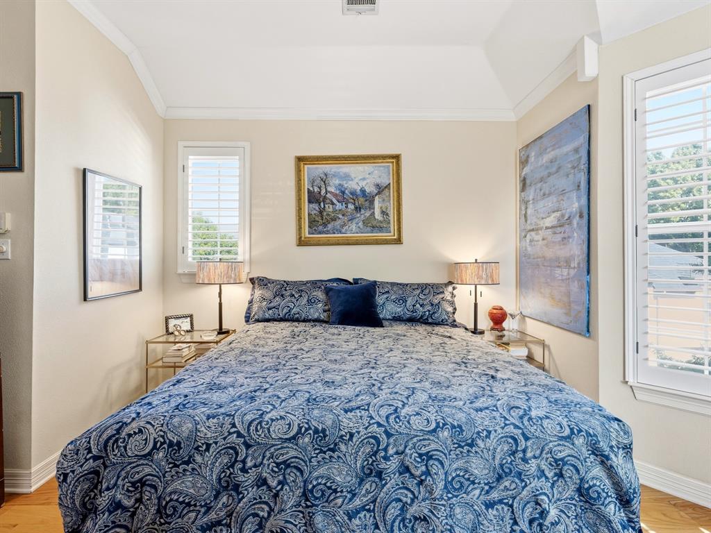 Vaulted ceiling, two windows featuring interior plantation shutters, and light-toned wood-finish flooring