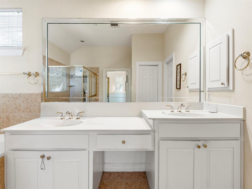 Dual-sink vanity with white cabinetry, light-toned countertop, large-format mirror, and brushed-finish fixtures