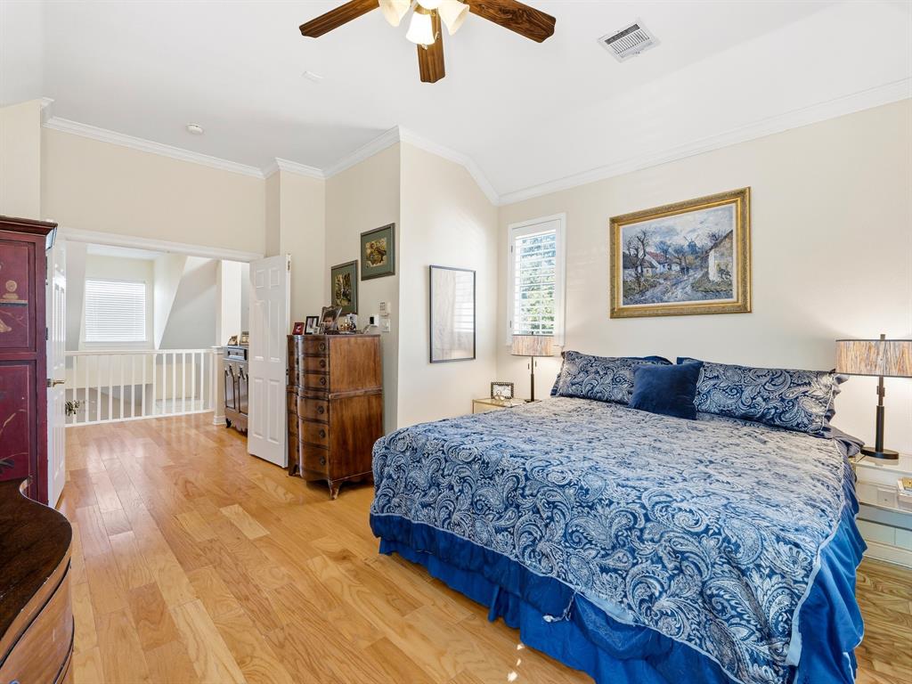 Vaulted ceiling featuring a central wooden-finish ceiling fan, natural wood-finish flooring, and crown molding