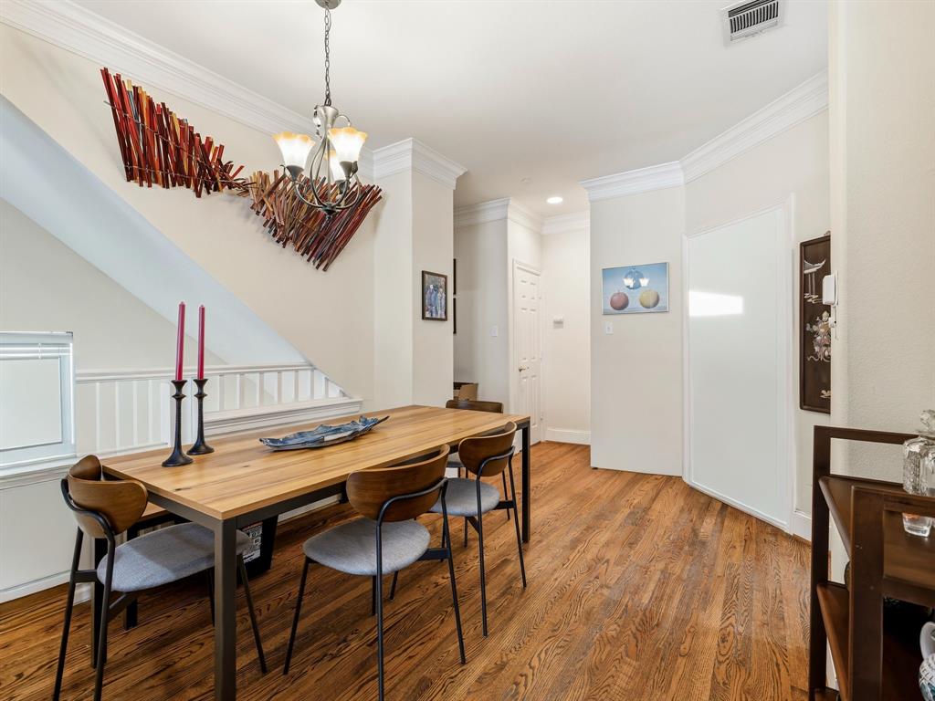 Interior space featuring wood-finish flooring, crown molding, a multi-light chandelier, and a decorative sloped wall