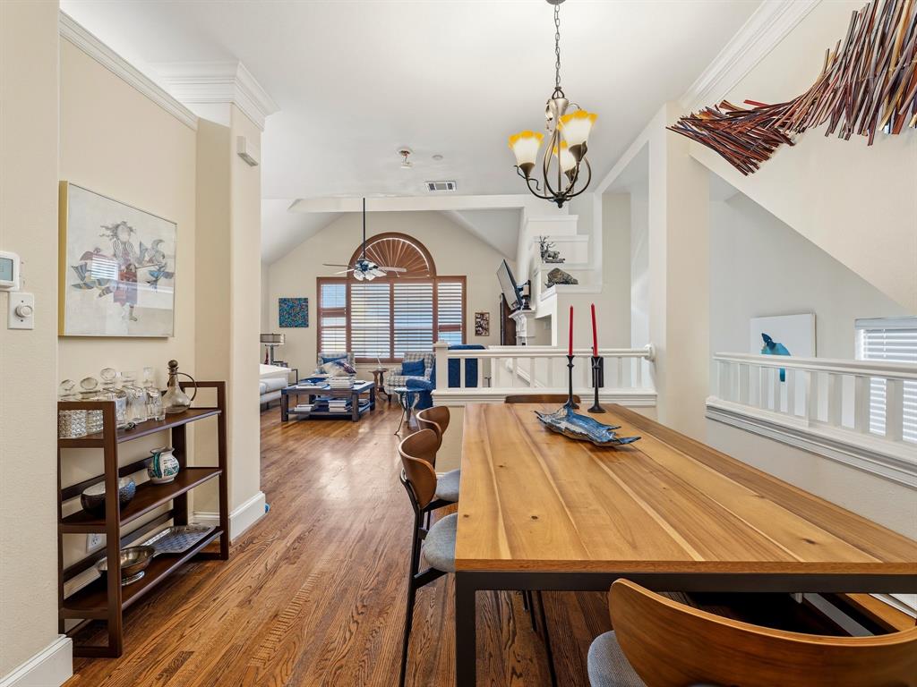 Dining area featuring wood-finish flooring, crown molding, and a multi-light chandelier, with a vaulted ceiling and arched window