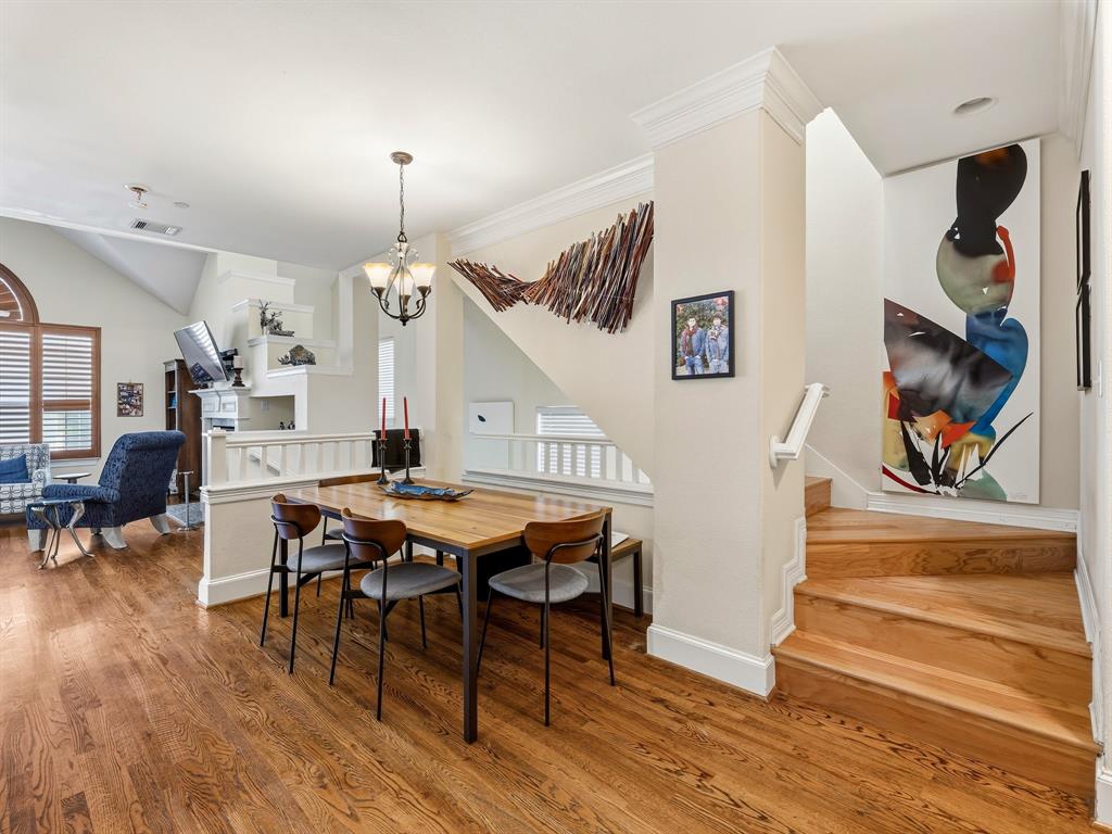 Hardwood flooring, crown molding, open-tread wood staircase with a white handrail, and a tiered architectural fireplace feature