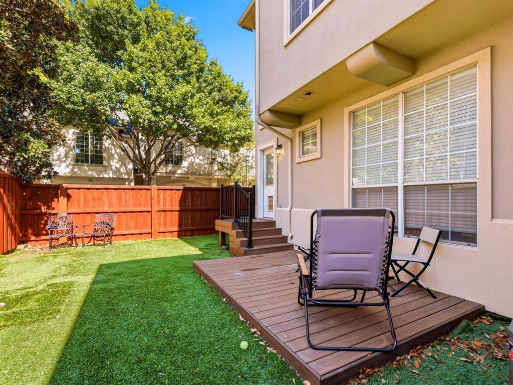 Private backyard featuring a wooden deck with stairs, synthetic turf lawn, and perimeter wood fencing