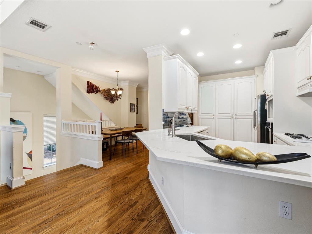 Kitchen featuring white cabinetry, solid-surface countertops, wood-finish flooring, recessed lighting, and crown molding
