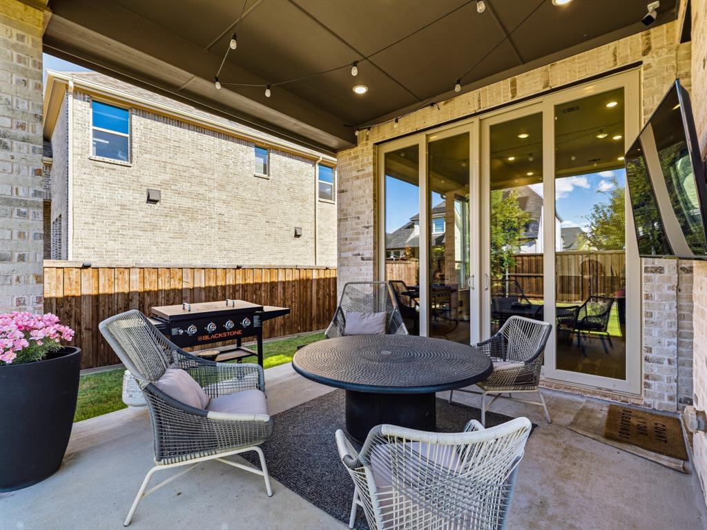 Covered patio featuring concrete flooring, brick exterior masonry, and multi-panel sliding glass doors