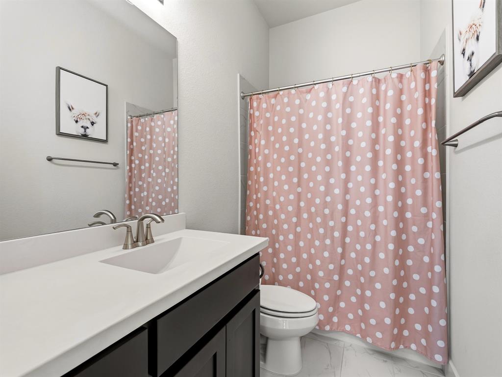 Dark-finish vanity featuring an integrated basin, brushed nickel faucet, large wall-mounted mirror, and tile flooring