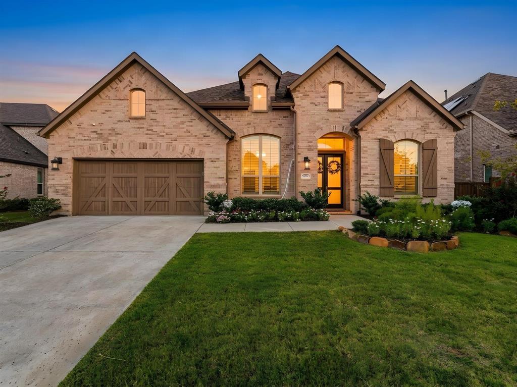 Brick exterior featuring multiple gables, arched window details, wooden shutters, and a multi-car garage with carriage-style doors Brick exterior featuring multiple gables, arched window details, wooden shutters, and a multi-car garage with carriage-style doors