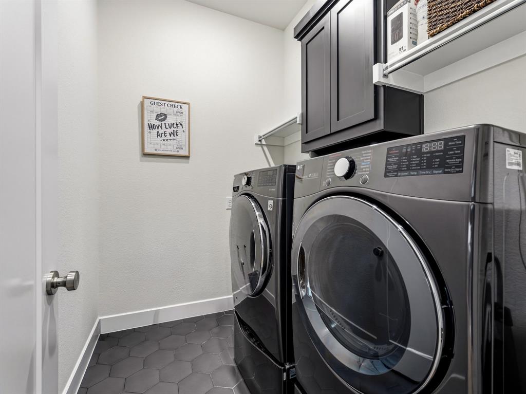 Laundry room featuring dark-finish wall-mounted cabinetry, white shelving, and charcoal hexagonal tile flooring