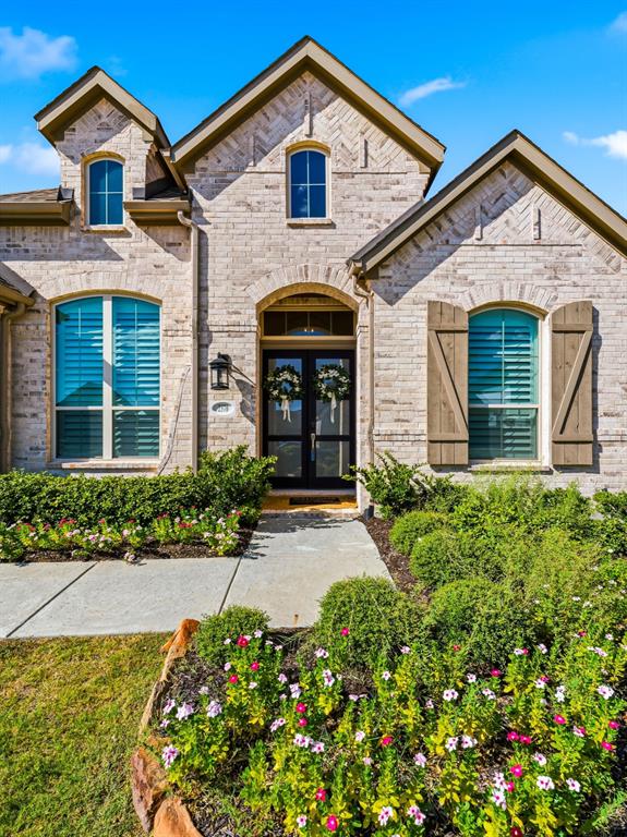 Multi-gabled brick exterior featuring arched window detailing, decorative wood shutters, and a covered entry with double glass-paneled doors