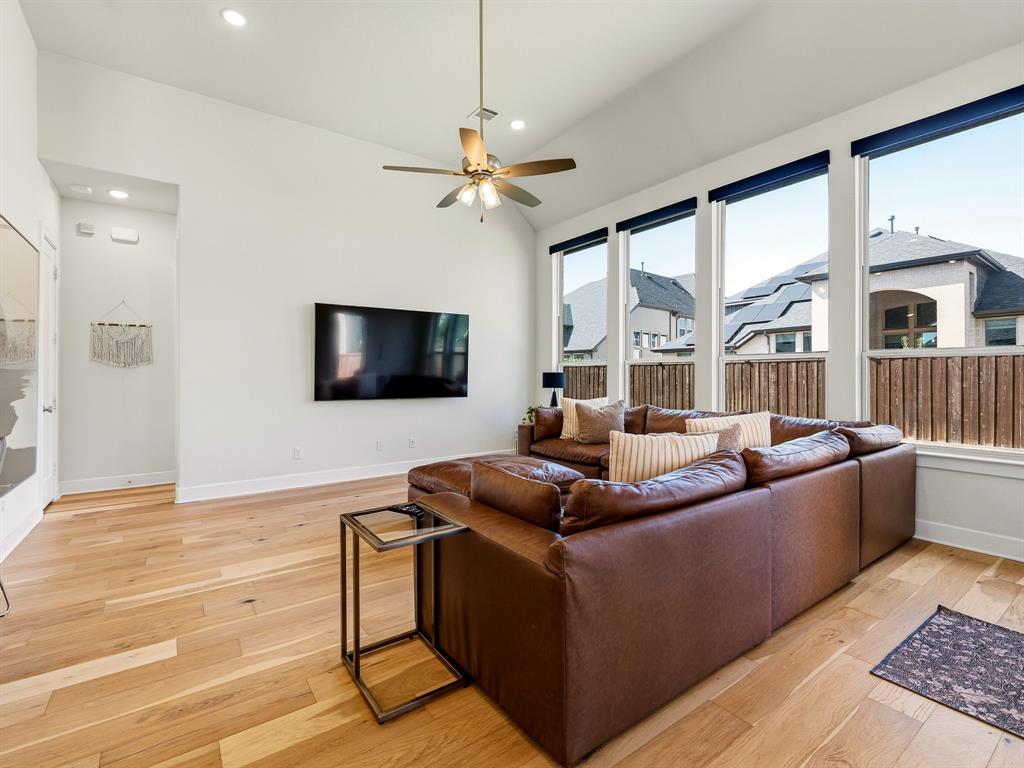 Vaulted ceilings, expansive windows, wood-finish flooring, and integrated ceiling fan