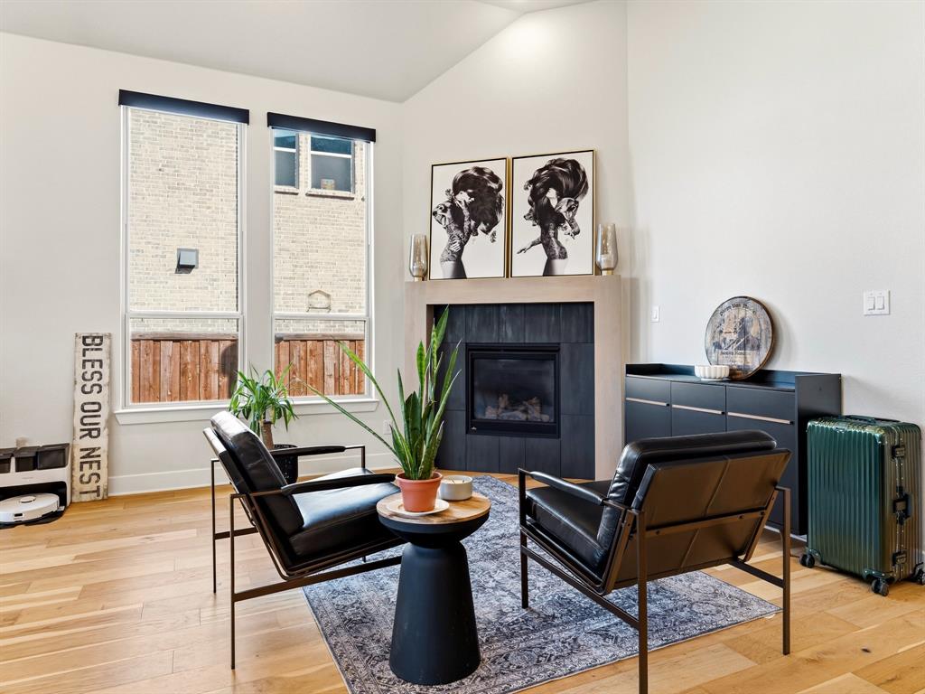 Vaulted ceiling, wood-finish flooring, floor-to-ceiling windows, and a fireplace featuring dark tile surround and a natural finish mantel