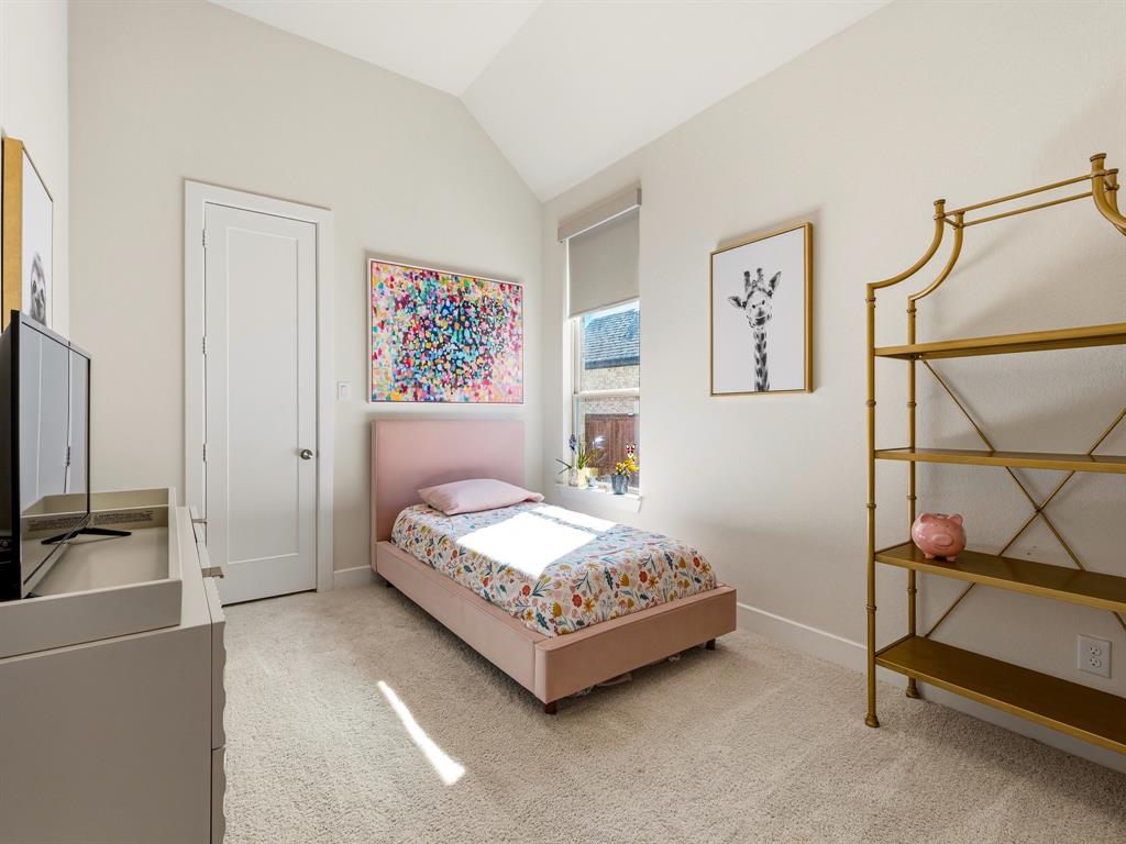 Vaulted ceilings featuring neutral wall paint, carpeted flooring, a single-panel interior door, and a tall window with an installed roller shade