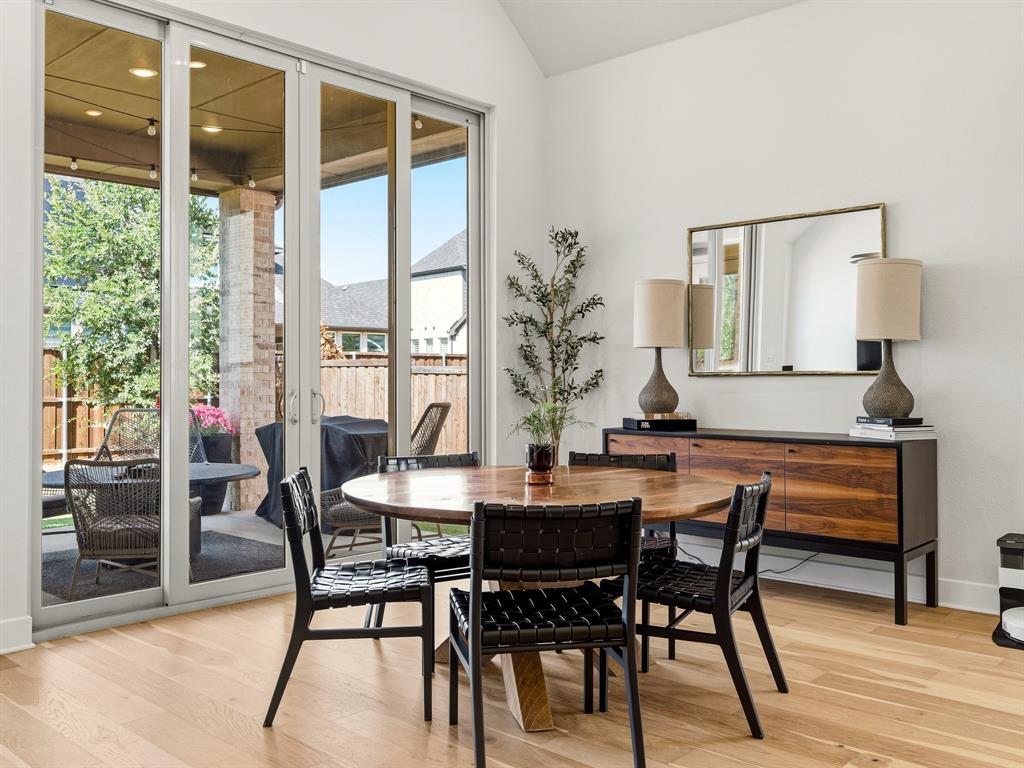 Vaulted ceiling, wood-finish flooring, and multi-panel sliding glass doors opening to a covered patio