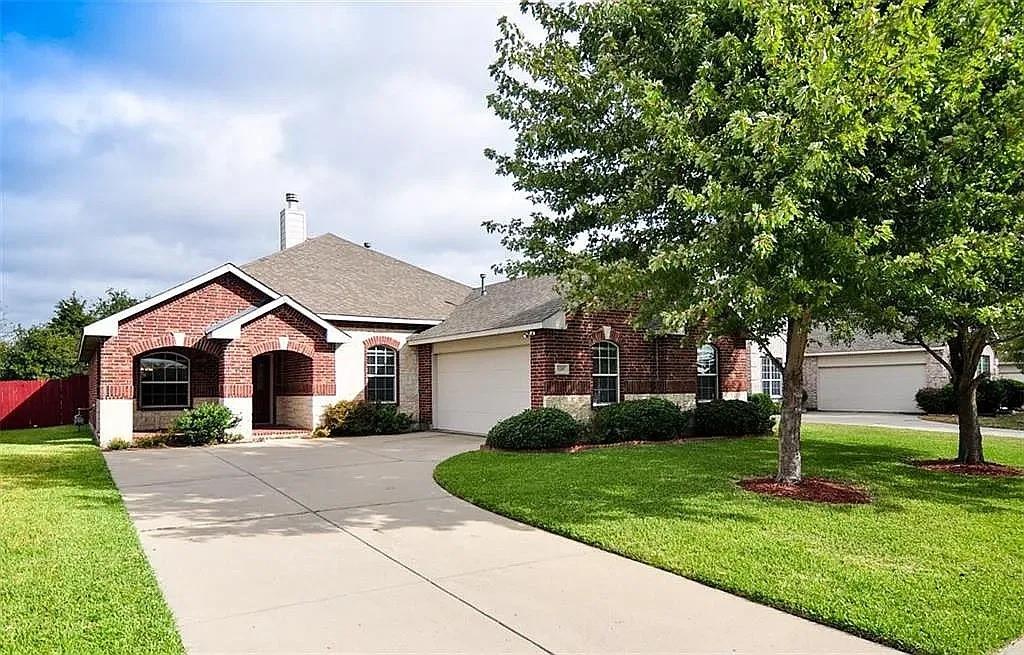Single-story brick exterior featuring a covered entryway, attached multi-car garage, arched window accents, and a concrete driveway Single-story brick exterior featuring a covered entryway, attached multi-car garage, arched window accents, and a concrete driveway