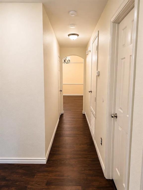 Hallway featuring wood-finish flooring, white panel doors, recessed ceiling lighting, and an arched entry Hallway featuring wood-finish flooring, white panel doors, recessed ceiling lighting, and an arched entry