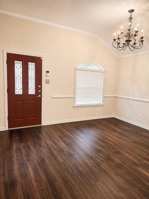Vaulted ceiling with an arched window, wood-finish flooring, decorative chair rail molding, and a multi-arm chandelier Vaulted ceiling with an arched window, wood-finish flooring, decorative chair rail molding, and a multi-arm chandelier