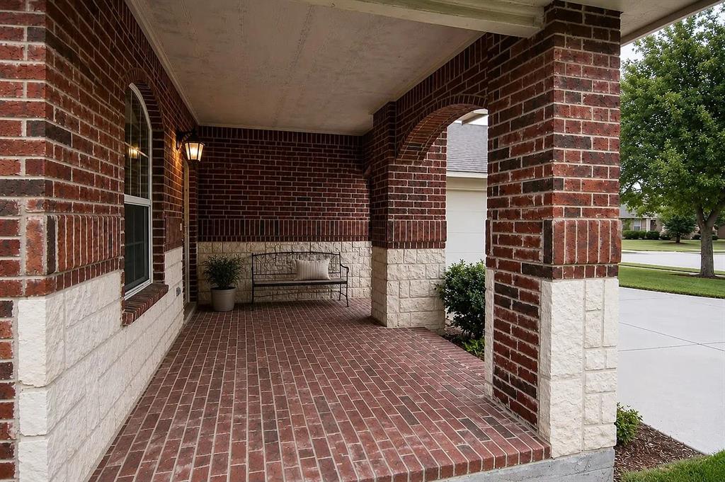 Covered front porch featuring red brick flooring, arched architectural detailing, masonry columns, and a mixed brick and stone facade Covered front porch featuring red brick flooring, arched architectural detailing, masonry columns, and a mixed brick and stone facade