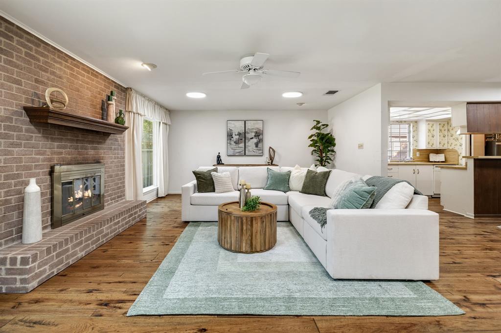 Living area featuring wood-finish flooring, a floor-to-ceiling brick fireplace with a wood mantel, and integrated ceiling lights