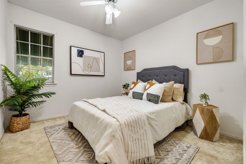 Bedroom featuring neutral-toned carpeting, a multi-pane window, and a ceiling-mounted light fixture with a fan