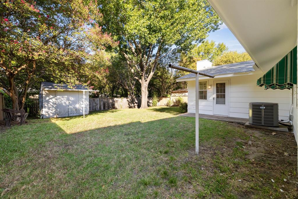 Backyard featuring a manicured lawn, mature trees, exterior storage shed, and white horizontal siding