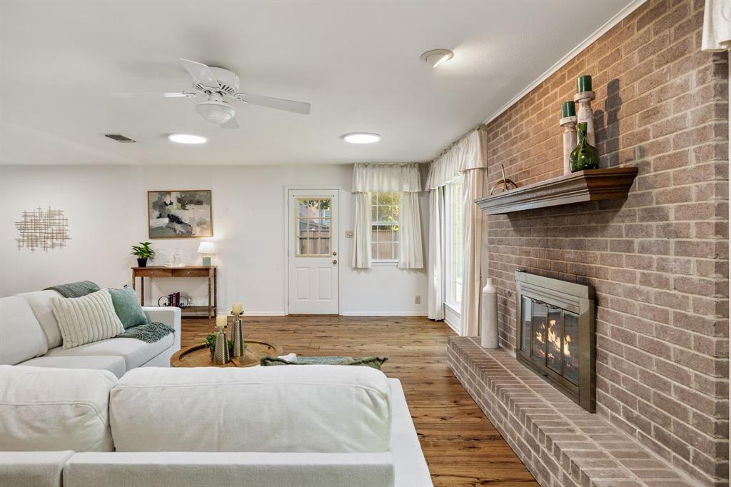Living space featuring wood-finish flooring, a floor-to-ceiling brick fireplace with a wood mantel, a ceiling fan, and recessed lighting