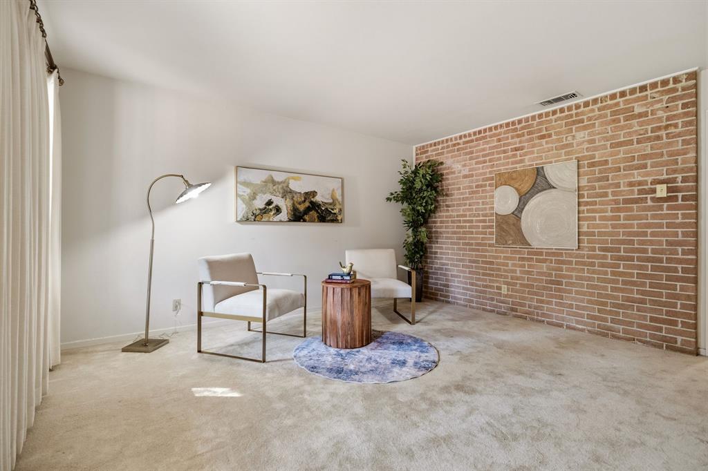 Interior space featuring a floor-to-ceiling brick accent wall and neutral carpeting Interior space featuring a floor-to-ceiling brick accent wall and neutral carpeting