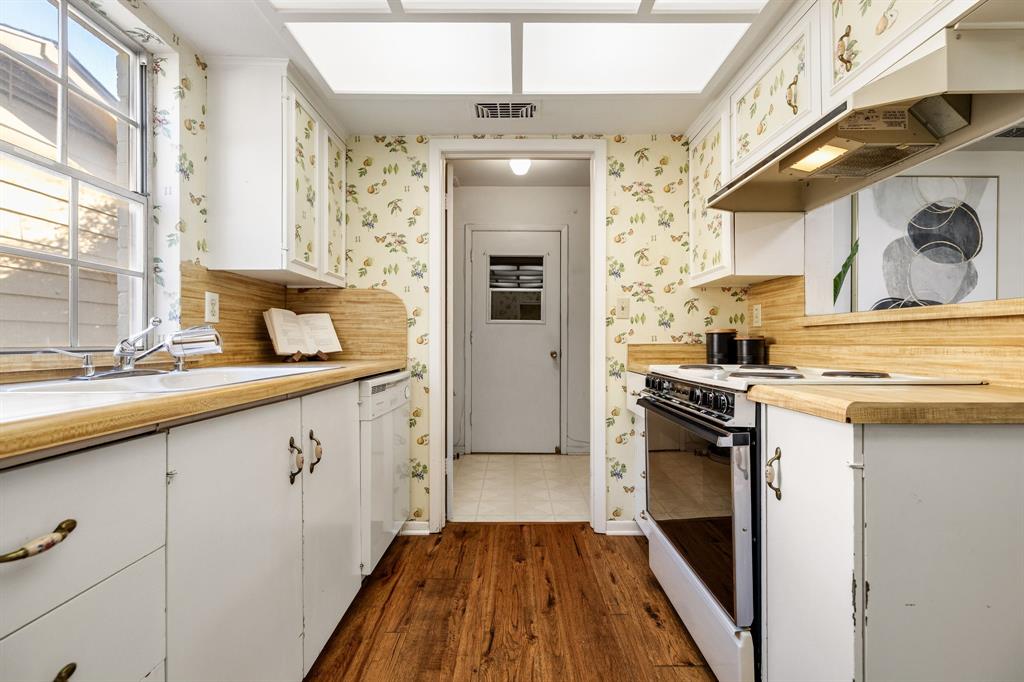 Kitchen featuring wood-finish flooring, white cabinetry, integrated range, wood-finish backsplash, and a multi-pane window
