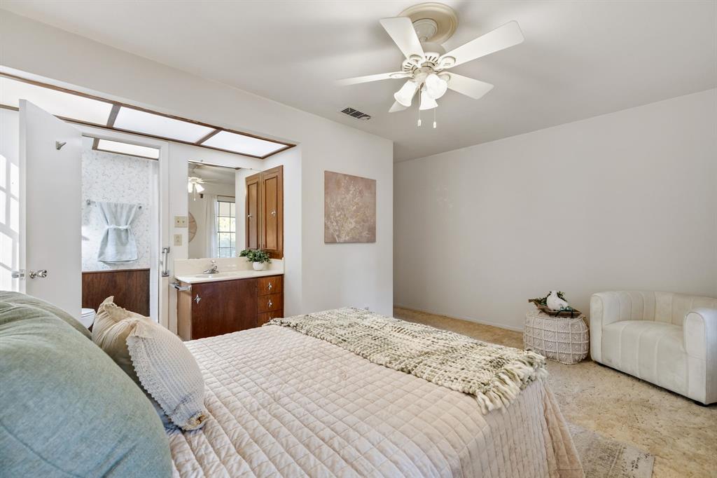 Bedroom featuring a neutral color palette, ceiling fan with multi-light fixture, carpeted flooring, and a built-in vanity with wood-finish cabinetry