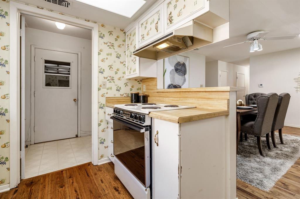 Kitchen featuring wood-finish countertops, white cabinetry with patterned upper doors, a white electric range, and wood-finish flooring