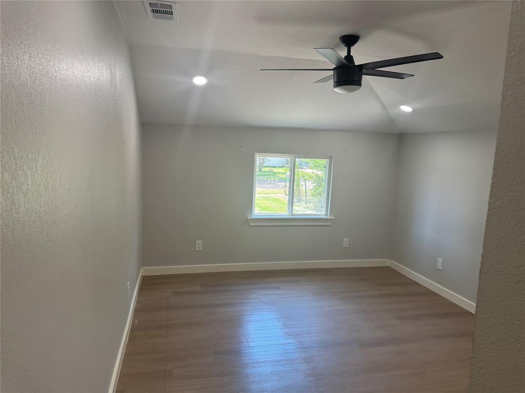 Room featuring a vaulted ceiling, wood-finish flooring, recessed lighting, and a matte black ceiling fan