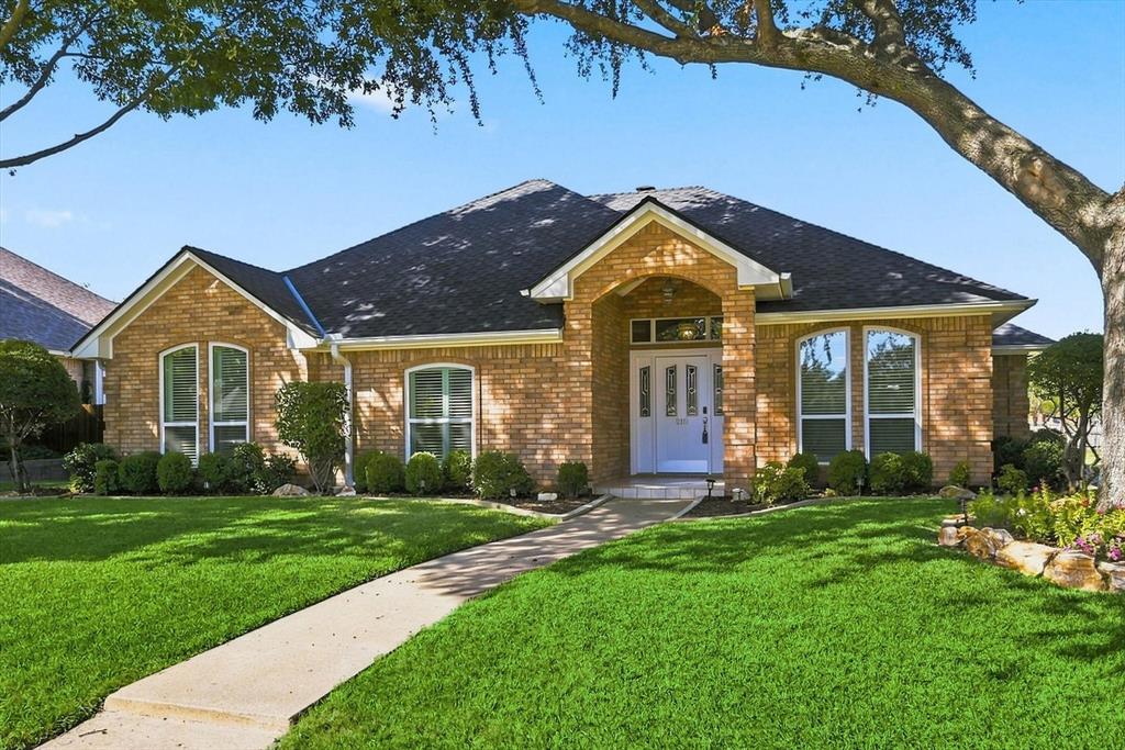 Brick exterior with a covered arched entryway, high-pitched roofline, decorative glass-paneled front door, and manicured front lawn