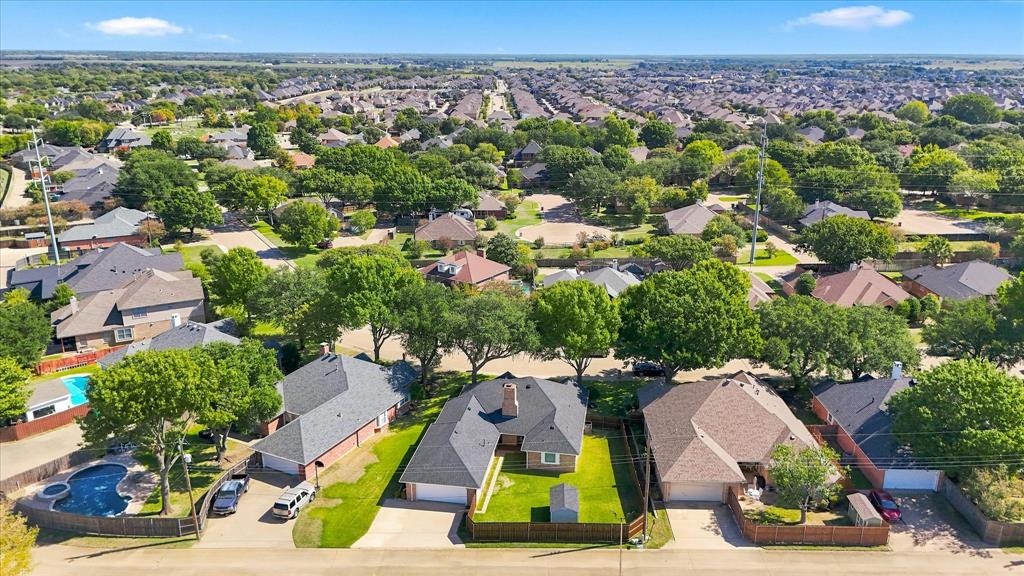 Aerial perspective featuring residential lots with established mature trees, manicured lawns, and varied rooflines