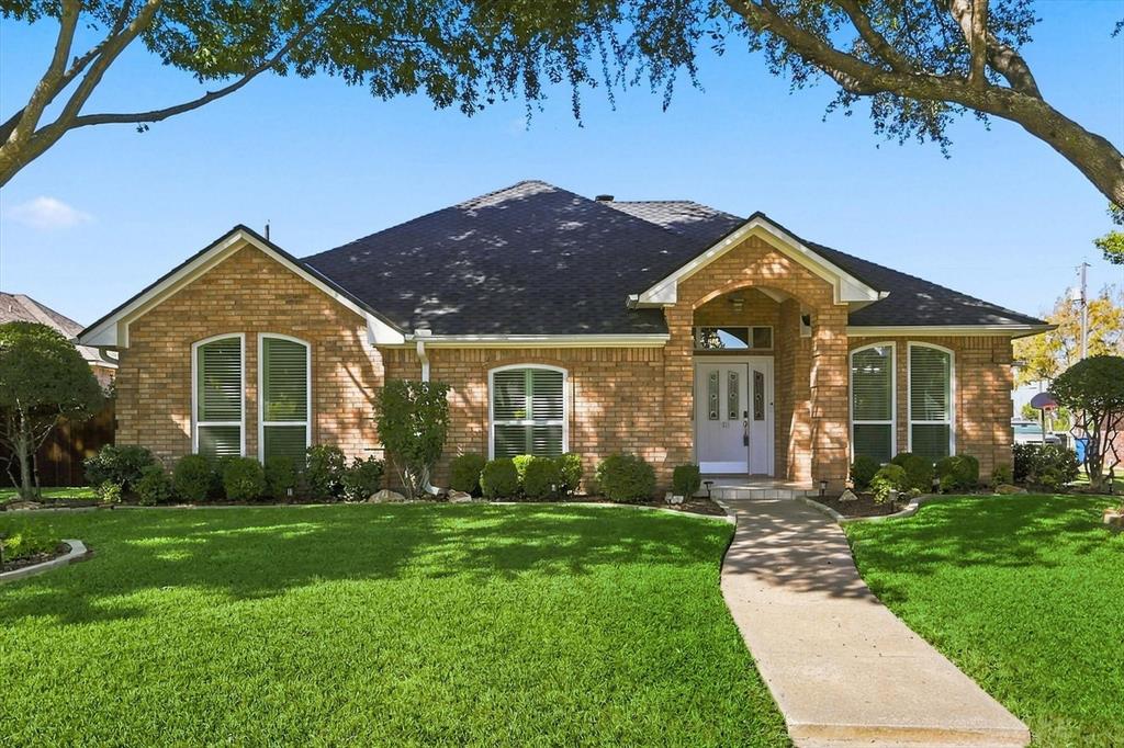 Single-story brick exterior featuring a multi-gabled roofline, arched windows, and a covered entryway with a decorative front door