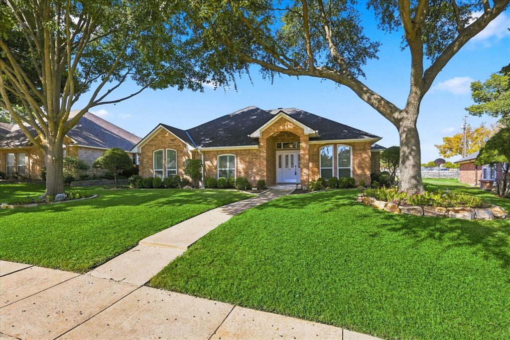 Single-story brick exterior featuring a multi-gabled roofline, arched windows, covered entryway, and mature landscape trees