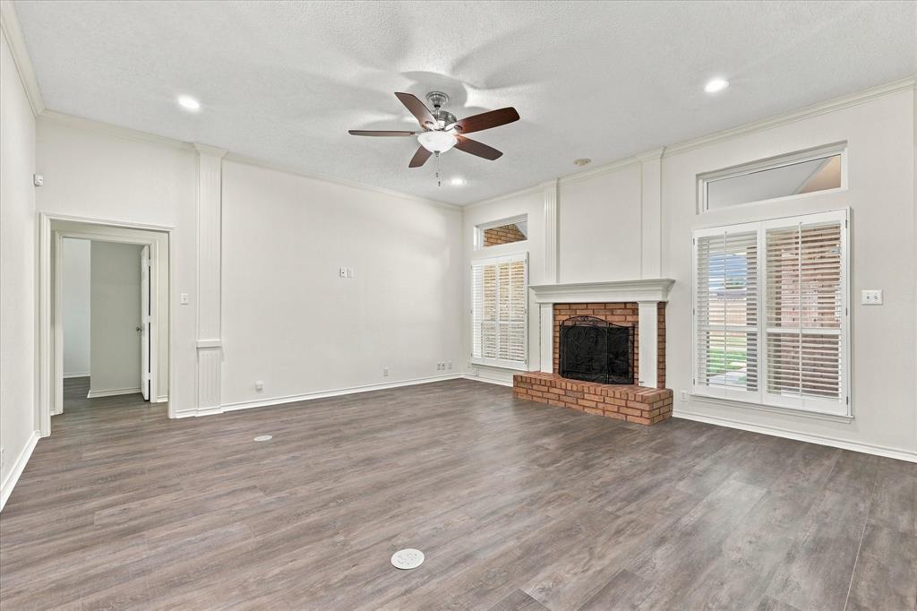 Living area featuring wood-finish flooring, recessed lighting, a brick fireplace with a mantle, and tall windows with plantation shutters