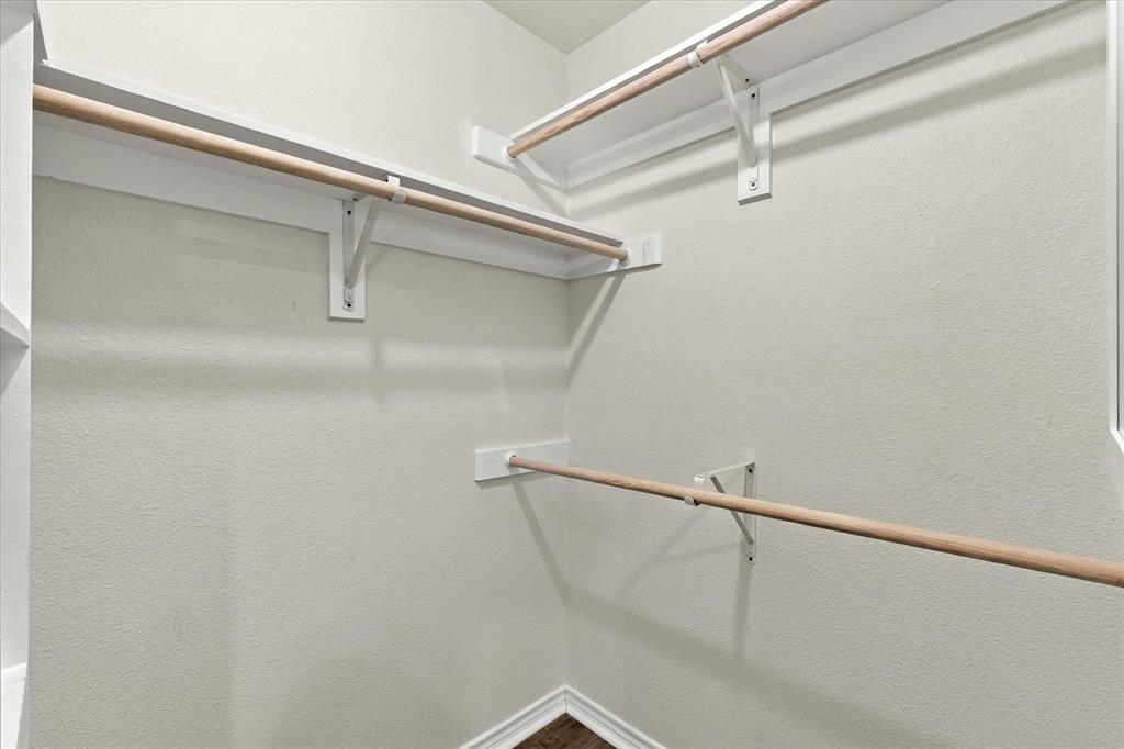 Walk-in closet featuring multi-level wood hanging rods and built-in shelving