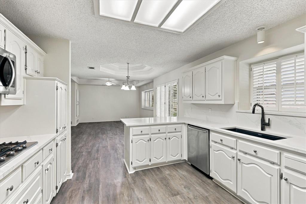 Kitchen featuring white cabinetry, wood-finish flooring, stone-style countertops, stainless steel appliances, and a matte black gooseneck faucet