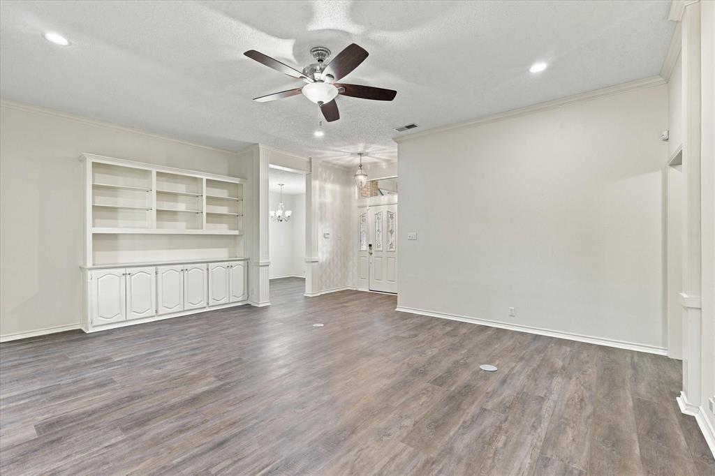 Interior space featuring wood-finish flooring, built-in cabinetry with glass shelving, recessed lighting, and a multi-blade ceiling fan