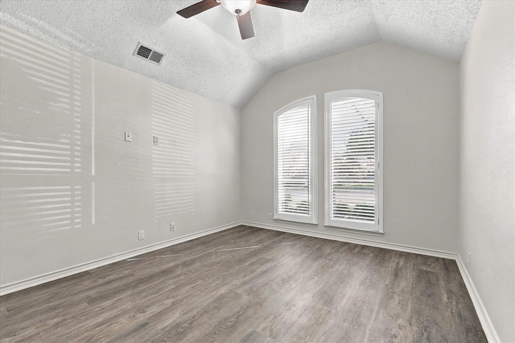 Room featuring vaulted ceilings, wood-finish flooring, and arched windows