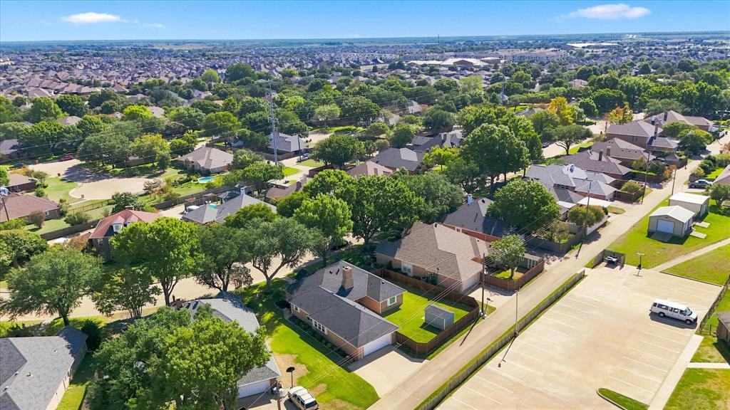 Aerial perspective featuring a brick exterior residence, gabled roofline, concrete driveway, and a fenced backyard